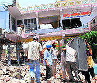 Devotees remove furniture from inside the temple during the pulling down of portions of the buildings in Amritsar on Wednesday.