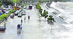 High tide in Mumbai: People walk on a flooded Marine Drive in Mumbai on Thursday