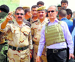 Kirkuk provinces governor Najim al-Din Omar Karim, wearing a bullet-proof vest, listens to an officer as the troops are deployed between Kirkuk, Mosul and Baiji in Iraq on Thursday; and (right) an image made from a video shows a militant standing in front of a burning Iraqi army Humvee in Tikrit.