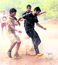 Boys enjoy the rain while playing football in Sector 22, Chandigarh, on Friday