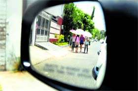 A rear view mirror of a car shows girls protecting themselves from the sizzling sun on a hot Saturday in Ludhiana.