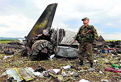An armed pro-Russian separatist stands guard at the site of the crash of the Il-76 Ukrainian army transport plane in Luhansk.