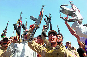 Iraqi Shiite men, some of them wearing military fatigues and guns given by the government, raise their weapons in Diyala province on Saturday.