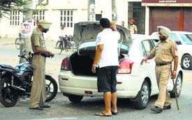 Police personnel check a vehicle and a motorcycle (below) at a naka in BRS Nagar. 
