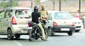 Police personnel check a vehicle and a motorcycle (below) at a naka in BRS Nagar. 