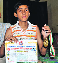 Vishal Sharma shows the gold medal and merit certificate won by him in a national karate meet, at his residence in Dadu Majra, Chandigarh, on Monday.
