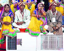 Couples sit next to an air conditioner as they wait for the start of a mass wedding ceremony in New Delhi