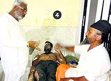Punjab Health Minister Surjit Kumar Jyani interacts with a patient and his attendant during a surprise visit to Civil Hospital in Barnala on Sunday night