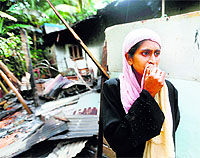A woman stands next to her burnt house after a clash between Buddhists and Muslims in Aluthgama on Monday.
