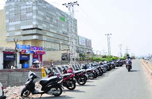 Vehicles parked illegally alongside a busy road near Wave Mall in Jammu on Tuesday