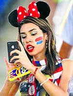 A teenager catches up with her friends on phone before the start of the US-Ghana match