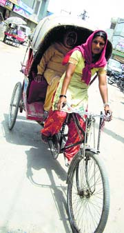 Jinder ferries a passenger in her rickshaw.