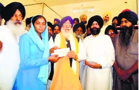 SGPC chief Avtar Singh Makkar hands over a cheque to a family member of a Sikh farmer displaced from Haryana.
