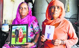 Praying for their safe return: Chalti Devi and Chander Walti of Rampura village in Karnal show photographs of their sons, who are stuck in Iraq.