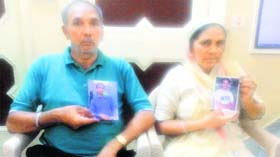 Jeet Ram and his wife Krishan Devi show photographs of their son Perminder Singh, who was among the 40 persons kidnapped from the Iraqi city of Mosul.