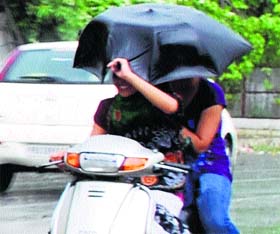 Girls enjoy a ride on scooter in the rain in Amritsar on Saturday.