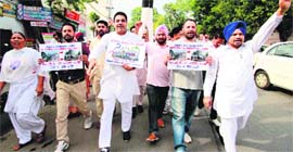 Congress workers stage a protest, seeking a rollback of the hike in the rail fares in Amritsar on Saturday.