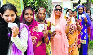 Women stand in a queue outside a poll booth at Meeti Beri in Dehradun during the panchayat polls on Saturday. 