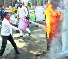 Activists of the Dogra Front douse the flames after setting afire an old refrigerator in Jammu on Sunday.