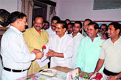 President of the Uttarakhand Congress Kishore Upadhayay gives a flower to a railway official as part of a protest against the rail fare hike at Dehradun railway station on Monday.