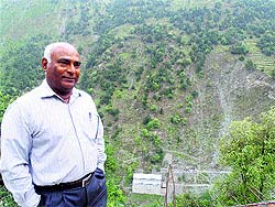Dr SK Saini stands against the backdrop of the 1.5-mw micro-hydel project near Holi in Chamba.