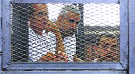 Al-Jazeera journalists (L-R) Peter Greste, Mohammed Fahmy and Baher Mohamed stand behind bars at a court in Cairo.