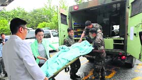South Korean Army personnel take conscript soldier, identified as Sergeant Lim, who shot and killed five comrades, to hospital wrapped with a blanket, in Gangneung on Monday.