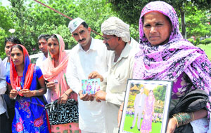 Family members show pictures of their kin stranded in Iraq as they seek help from the district administration for their safe return at the Mini-Secretariat in Karnal on Tuesday.