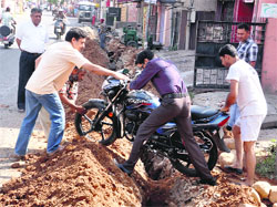 Residents try to get a motorcycle out of a house as the road in front of the gate has been dug in Jammu. Tribune photo: Anand Sharma