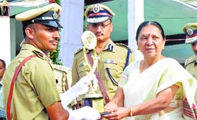 Gujarat CM Anandiben Patel presents an award to a police sub-inspector in Karai near Ahmedabad on Tuesday.
