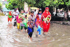 Devotees walk through a waterlogged street near the Golden Temple after a spell of heavy pre-monsoon showers in Amritsar on Wednesday.   