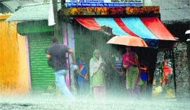 People try to take shelter from sudden rain at Dharamsala on Wednesday.