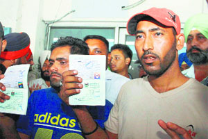 Punjabi workers Jagpreet and Kamaldeep (R) show their passports after their return from Iraq, in Jalandhar.