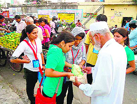 Volunteers of the U-turn Foundation distribute cloth bags to buyers as part of the anti-polythene campaign at Nehru Colony in Dehradun on Friday.