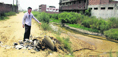 An employee of the Drainage Department shows a severed connection through which dairies were dumping untreated water into the Kala Sanghian drain in Jalandhar.