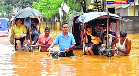 Rickshaw-pullers wade through a waterlogged street after heavy rains in Guwahati on Friday.