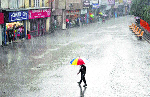 A man walks with an umbrella during heavy rain in Shimla on Saturday.