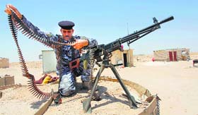 A member of the Iraqi security forces works with an ammunition belt near a weapon in the desert region between Kerbala and Najaf, south of Baghdad, on Saturday.
