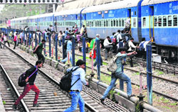 Candidates, who have come to appear in a railway exam, risk their life as they rush to catch a train leaving the Chandigarh Railway Station on Sunday. Tribune photo: Parvesh Chauhan