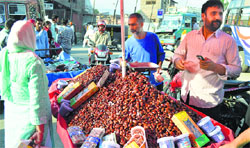 People buy dates from a roadside vendor on the eve of Ramadan in Srinagar on Sunday. Tribune photo: Amin War