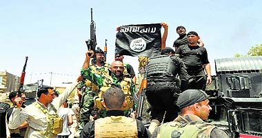 Iraqi security forces hold up a flag of the Islamic State in Iraq and the Levant they captured during an operation to regain control of Dallah Abbas, the capital of Iraqs Diyala province, 60 km from Baghdad, on Saturday. 