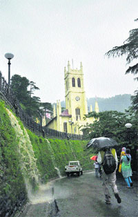 Commuters walk through heavy rain in Shimla on Monday.