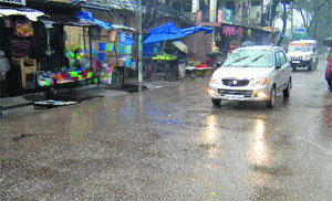 Vehicles with headlights on during rain at Kangra town on Monday.
