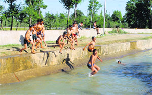 As the mercury rises, children take a plunge in a stream on the outskirts of Srinagar on Sunday.