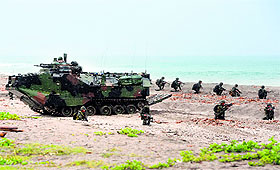 Philippine Marines take position next to a US amphibious assault vehicle during a mock beach assault as part of CARAT 2014 along the beach at a Philippine naval training base facing the South China Sea..