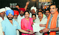 Villagers give a memorandum of their demands to Member of Parliament Kirron Kher during a meeting at Burail village in Chandigarh on Tuesday
