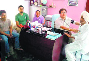 A doctor (wearing black badge) examines a patient in Hoshiarpur on Tuesday.