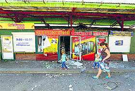 A woman and a child walk past a damaged street market in the Ukrainian eastern city of Slaviansk on Tuesday.