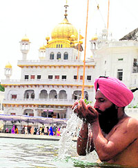 A devotee takes a dip in the holy sarovar on the ocassion of the 408th foundation day of the Akal Takht in Amritsar on Wednesday