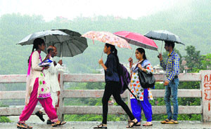 People out with their umbrellas after a spell of heavy rain in Mandi on Wednesday.